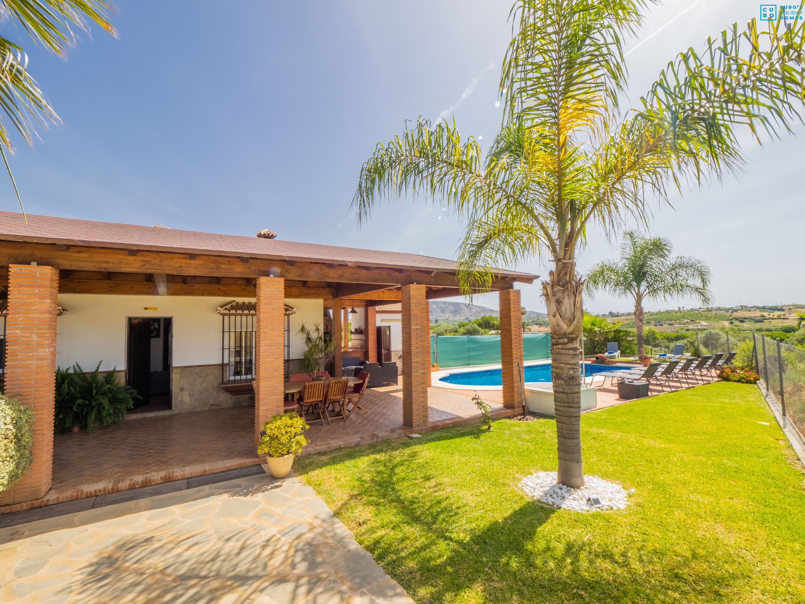 Vista del jardín, casa y piscina de la propiedad 