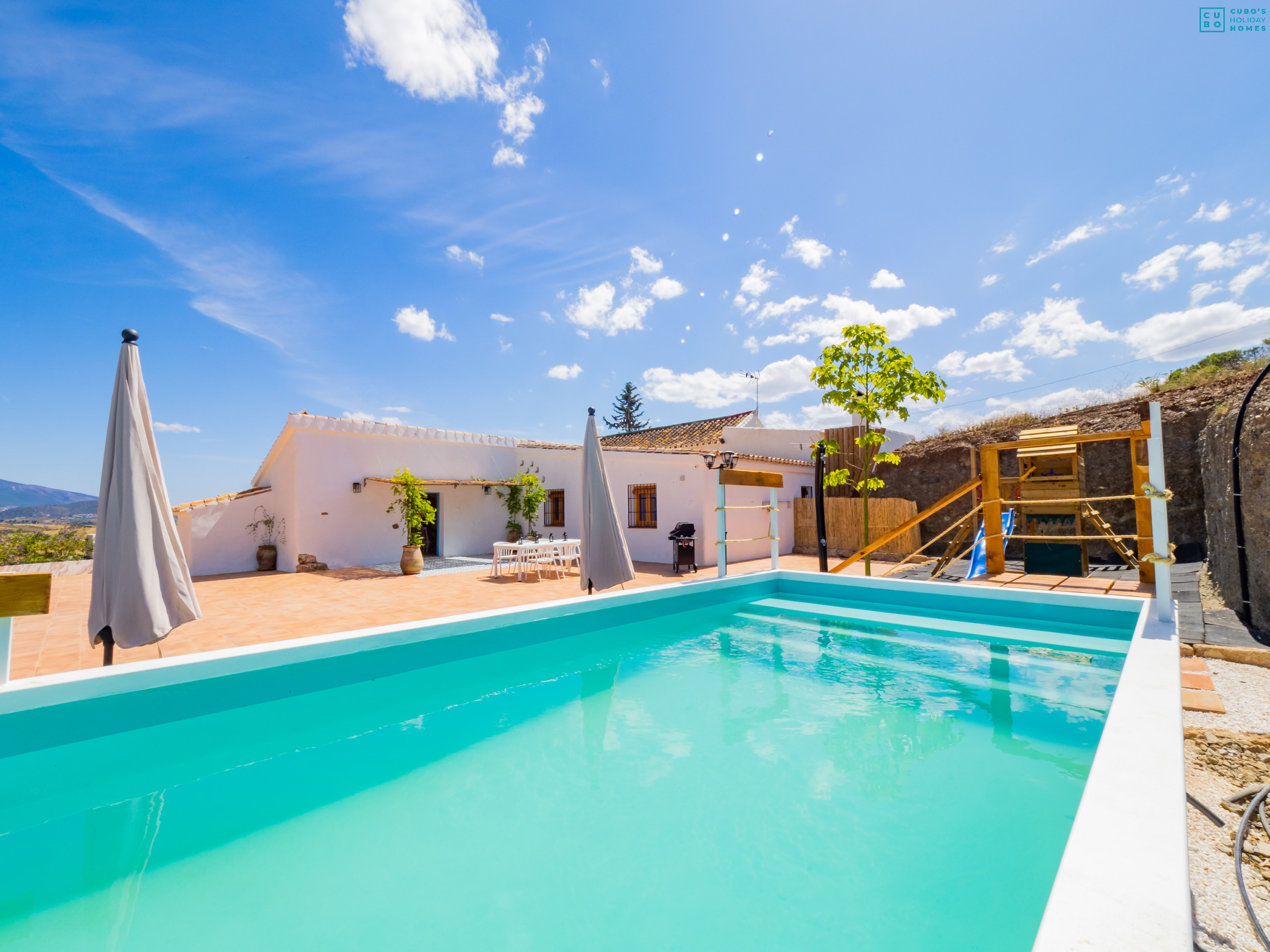 Piscine recyclée, aire de jeux et façade du logement.